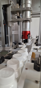 CC570 Capping Machine, Designed to fit over a conveyor new or existing. Image shows the capping head and bottles being fed into the machine.