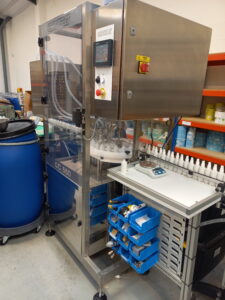 CC560 four head gear filler dispensing beauty products into mist bottles. with operators inserting the mister.