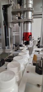CC570 Capping Machine, Designed to fit over a conveyor new or existing. Image shows the capping head and bottles being fed into the machine.