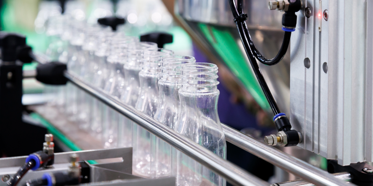 Uncapped bottles moving along a factory production line.